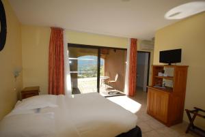 a bedroom with a bed and a balcony with a television at Logis Hôtel-restaurant La Mère Biquette in Saint-Pons
