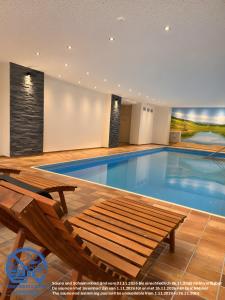 a large swimming pool with a wooden bench and a bench at Ferienwohnung Talblick in Schmallenberg