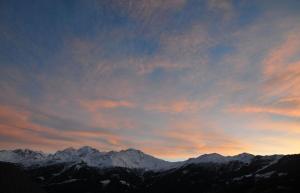 a sunset over a mountain range with snow covered mountains at Laiterie 1 in Verbier