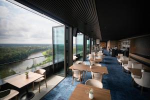 a restaurant with tables and chairs and large windows at Snow Hotel Druskininkai in Druskininkai