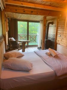 two beds in a room with a large window at Ayder Villas in Çamlıhemşin