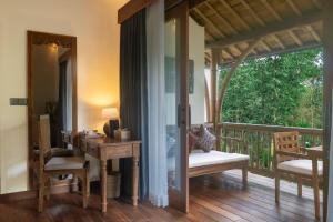 a room with a balcony with a table and chairs at The Compass Rose Valley in Ubud