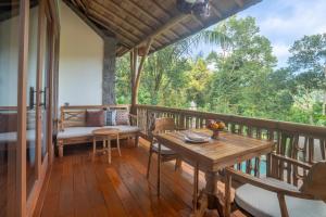 a porch with a table and chairs on a deck at The Compass Rose Valley in Ubud