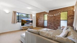 a living room with a couch and a brick wall at 4BR big family house with huge pool in Brisbane
