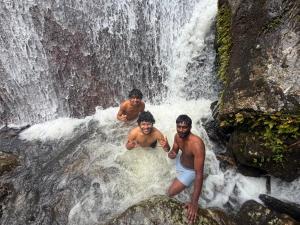 three men are standing in a waterfall at FREEDOM HOUSE, Munnar - A Backpackers Hostel in Munnar