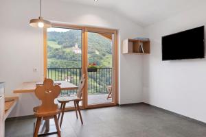 a living room with a dining table and a balcony at Oberstarzerhof in Barbiano
