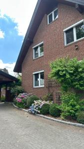 a red brick house with flowers in front of it at Haus Sonnenwest in Rosengarten