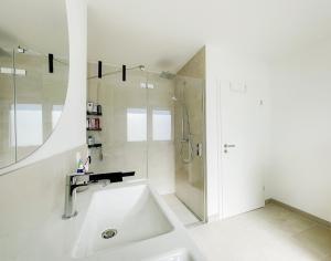 a white bathroom with a shower and a sink at 3S Holiday Home in Traunstein