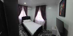 a small bedroom with a bed and two windows at MDY Apartments in Ile-Ife