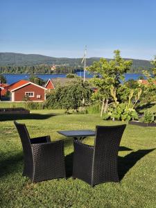 a table and chairs in the grass with a view of the water at Mysig timmerstuga på dalagård in Leksand +14 photos