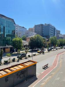 a view of a city street with a bench and buildings at Squarehouse Apartment Prishtina in Prishtinë