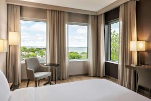 a hotel room with a bed and two chairs and large windows at AC Hotel by Marriott Madison Downtown in Madison +63 photos