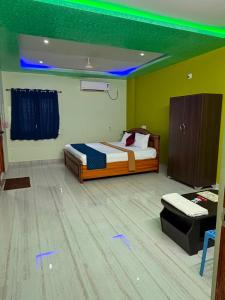 a bedroom with a bed in a room with green lighting at pnrpalace in Bāpatla