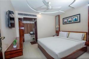 a bedroom with a large white bed and a bathroom at Hotel President in Madurai