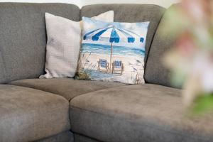 a pillow with an umbrella and chairs on a couch at Waldstraße 2 Ferienwohnung Volkenborn in Kellenhusen