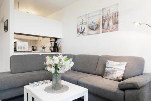 a living room with a couch and a table with flowers at Waldstraße 2 Ferienwohnung Volkenborn in Kellenhusen +27 photos
