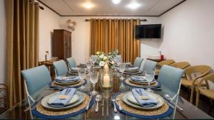 a dining room with a glass table and blue chairs at Mist Mountain Hiking Base in Pimbura