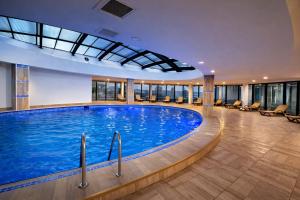 a large swimming pool in a hotel with chairs at Orbi City Panorama Hotel & Sea View Balcony in Batumi
