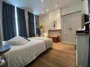 a bedroom with a white bed and blue curtains at B&B Villa Des Raisins in Bruges +52 photos