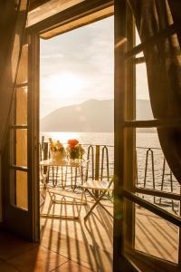 una mesa y sillas en un balcón con vistas al océano en Casa Dante, en Sale Marasino