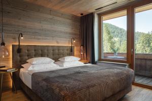 a bedroom with a large bed and a large window at Alpenhotel Kitzbühel am Schwarzsee - 4 Sterne Superior in Kitzbühel +67 photos