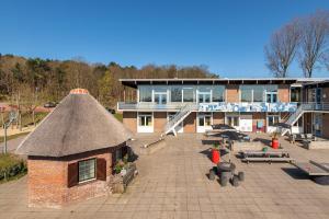 a building with a thatch roof and a patio at Stayokay Hostel Noordwijk in Noordwijk
