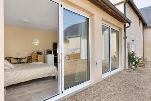 a sliding glass door leading to a patio with a bed at La Parenthèse du Loir in Château-du-Loir