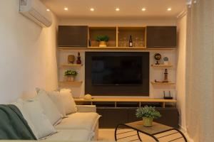 a living room with a white couch and a flat screen tv at Casa BACO - Morro de São Paulo in Cairu