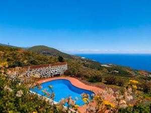 a swimming pool on a hill next to the ocean at Tomasín in Puntallana