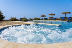 a jacuzzi tub in a resort with blue chairs at Change The World - Herdade Monte do Peral in Montes Juntos