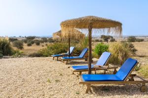 four lounge chairs and an umbrella on a beach at Change The World - Herdade Monte do Peral in Montes Juntos