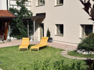 three yellow chairs sitting in the grass in front of a building at Karwendelnest in Maurach
