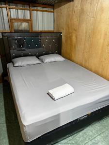 a bed with a black headboard and a white towel on it at Jufri Homestay in Kasijala