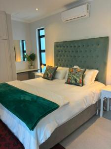 a bedroom with a large bed with a green headboard at House Foxglove in Paarl
