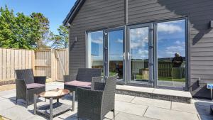 a patio with chairs and a table and windows at Birch Tree Lodge - Luxurious Lodge on the NC500 by Thrumster Lodges in Wick