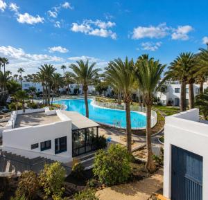 an aerial view of a resort pool with palm trees at Los Barqueros Suites Palm in Corralejo
