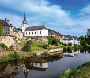 a village with a church and a river at Chez Eva & Léon in Florenville
