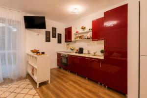 Eine Küche mit roten Schränken und einem Fernseher an der Wand. in der Unterkunft Wise Nest Studio with pool and spa in Sinaia