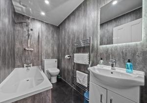a bathroom with a sink and a tub and a toilet at Albion Apartment by Klass Living Coatbridge in Coatbridge