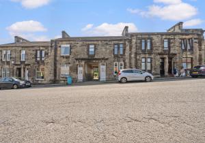 a large brick building with cars parked in front of it at Albion Apartment by Klass Living Coatbridge in Coatbridge