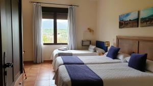 a hotel room with three beds and a window at Casa de dos habitaciones con piscina en Cabañeros in Navas de Estena