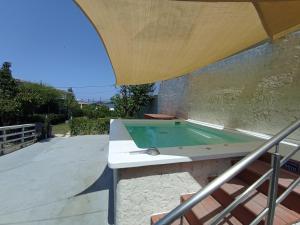 a swimming pool in a patio with an umbrella at Wooden Summer House in Mantoúkion