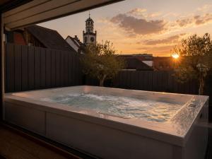 a hot tub on a balcony with a sunset in the background at Hotel Residenz in Ravensburg