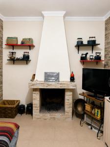 a living room with a fireplace and a tv at Casa Bia Olívia in Albernoa