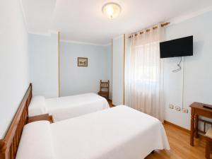 a hotel room with two beds and a flat screen tv at Hostal ** EC León in León
