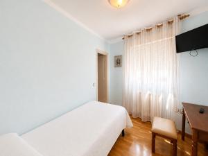 a white bedroom with a bed and a desk at Hostal ** EC León in León +23 photos