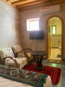a room with a bed and a table and a tv at Riad Nassar in Chefchaouen