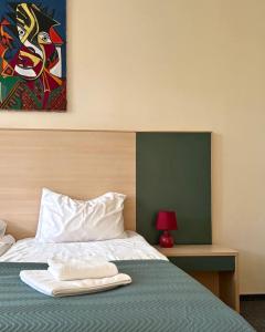 a bedroom with a bed with a painting on the wall at Palangos Dailė in Palanga