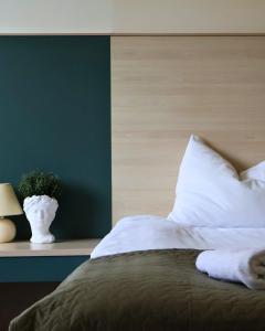 a bed with white pillows and a green wall at Palangos Dailė in Palanga