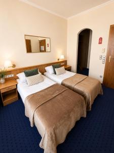 two beds in a hotel room with a mirror at Hotel Kreuzplatz Gießen Zentrum in Gießen